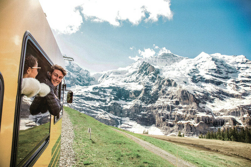 Two young travellers riding a train through alps