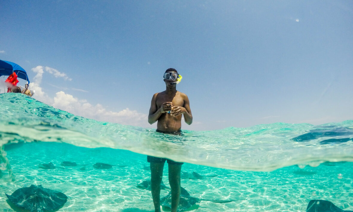 A man travels and snorkels in the water with stingrays.