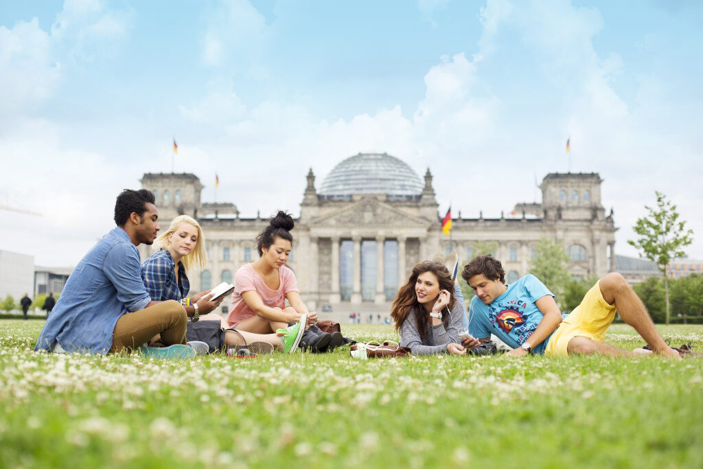 A group of students sitting on the grass in front of the Reichstag, one of Europe's top attractions.