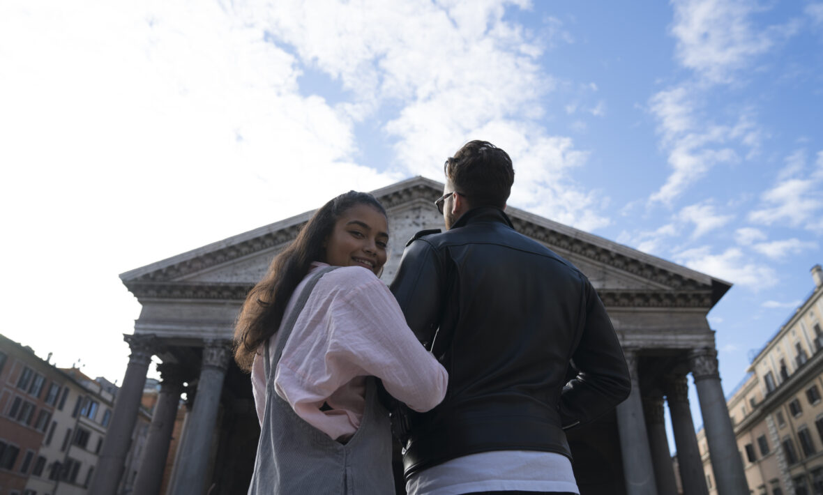 Couple with interlinked arms in front of grand old building