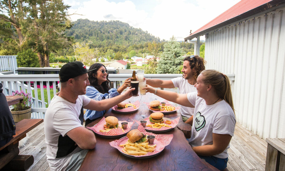 A group of people toasting at a table with plates of food during Mardi Gras.