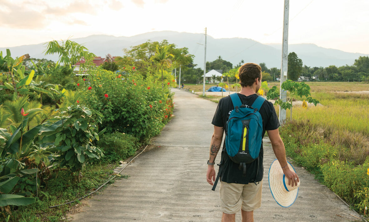 A man traveling with a backpack and a surfboard.