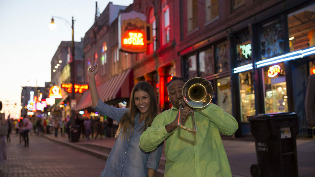 A man and a woman playing music on a city street.