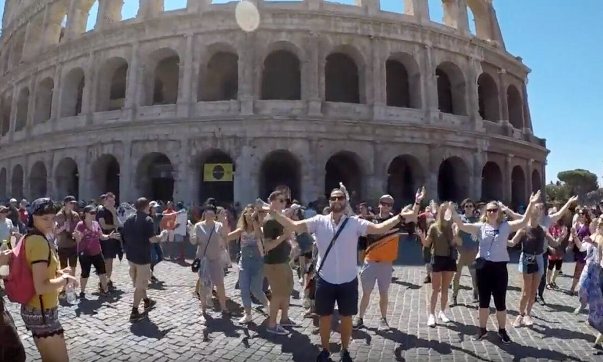 A flash mob stands in front of the colossion.