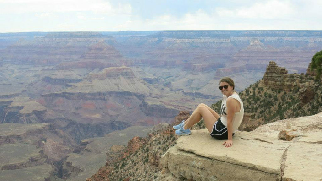 A woman contemplating her identity while sitting on the edge of a cliff overlooking the grand canyon.