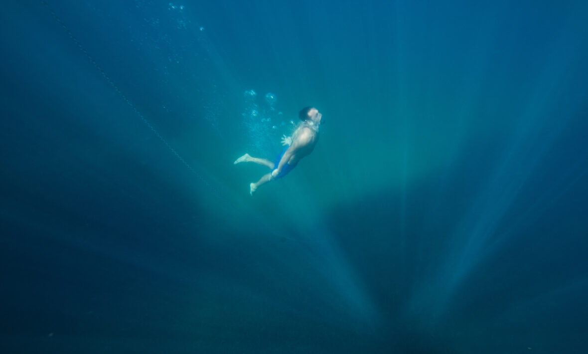 A man is swimming in the water near a dive shop in Borneo.