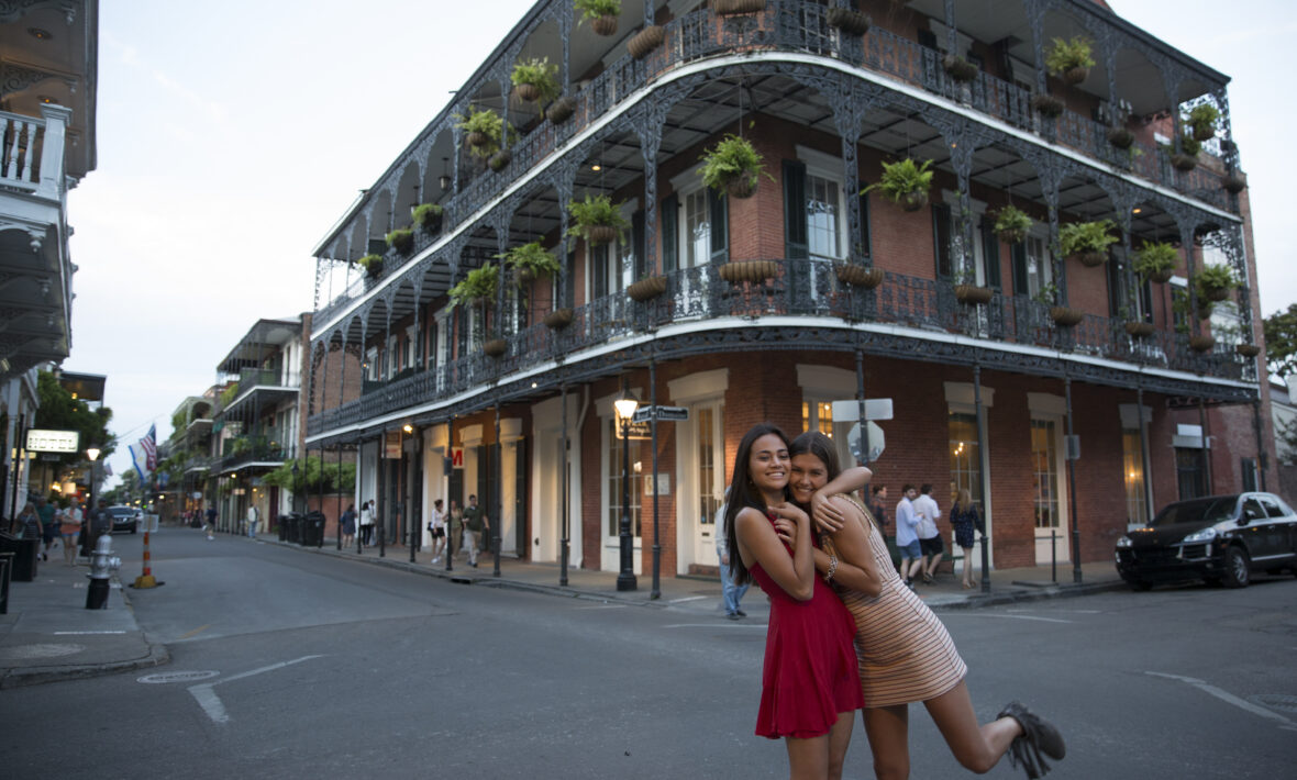 Women smiling at a crossroads with decorative American building