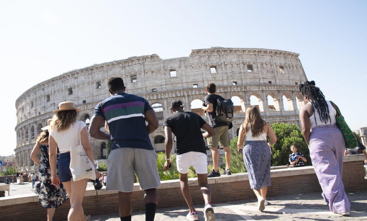 A group of people sightseeing in Rome in front of the colossion.