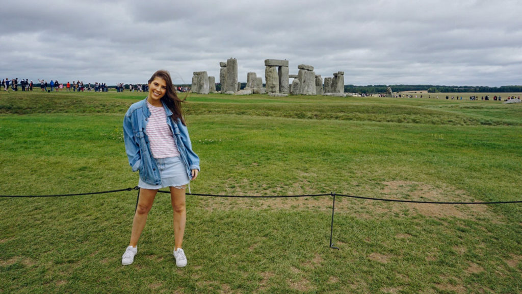 A woman posing in front of Stonehenge during her international exploration.