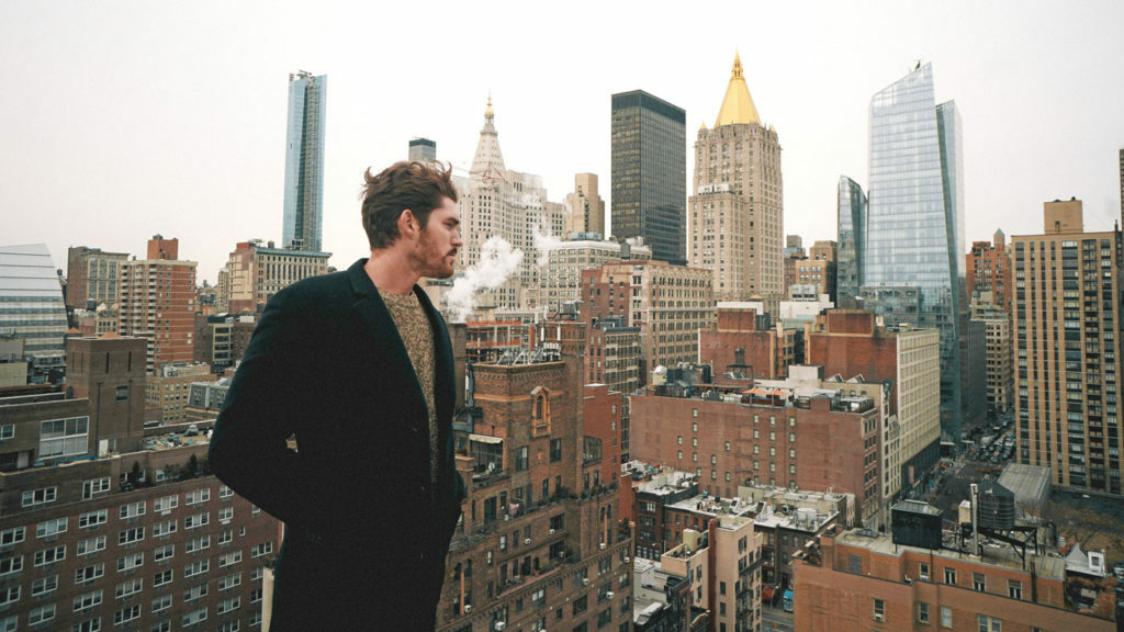 A man experiencing reverse culture shock on top of a building in New York City.