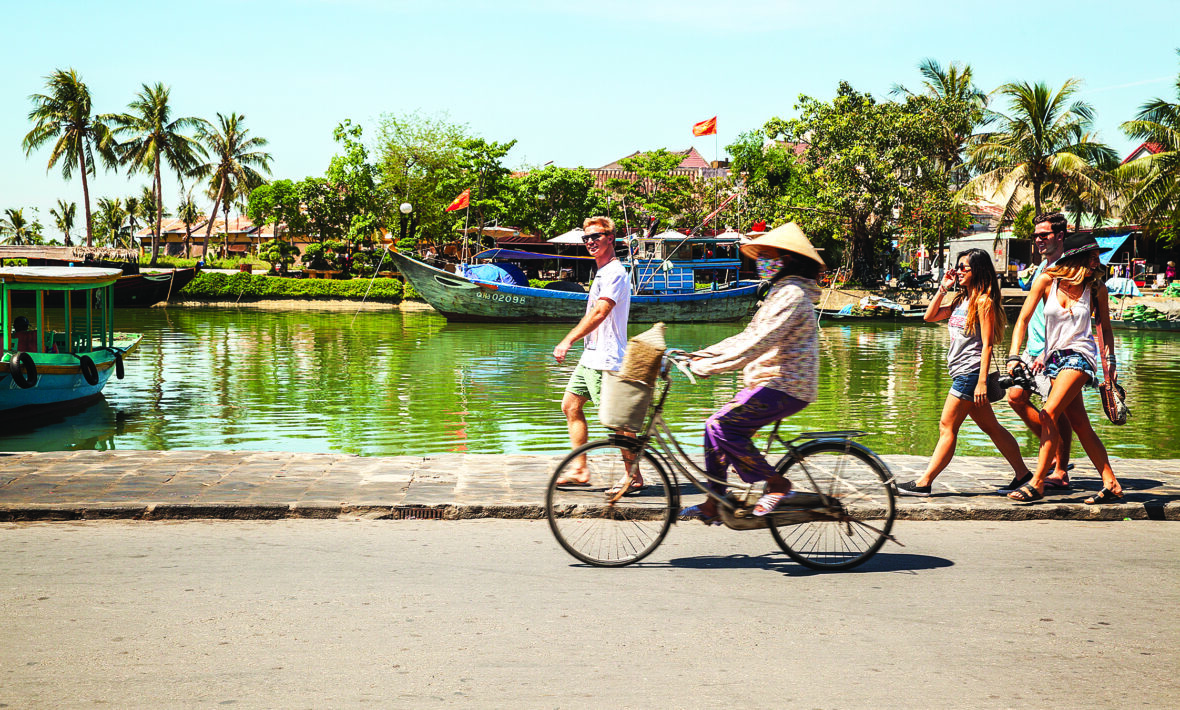 A group of people riding a bicycle near a body of water, seeking a cure for a break-up through adventure and camaraderie.