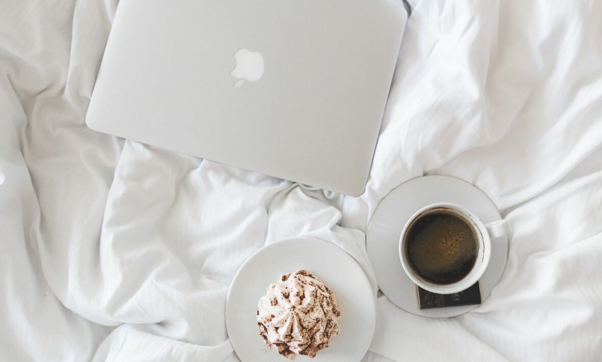 A bed with a laptop and a cup of coffee, envisioning success post-covid.