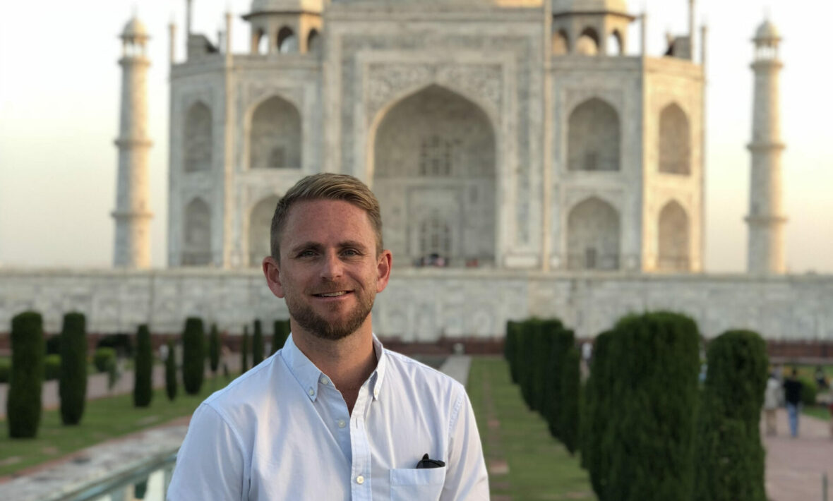 A man poses in front of the Taj Mahal.