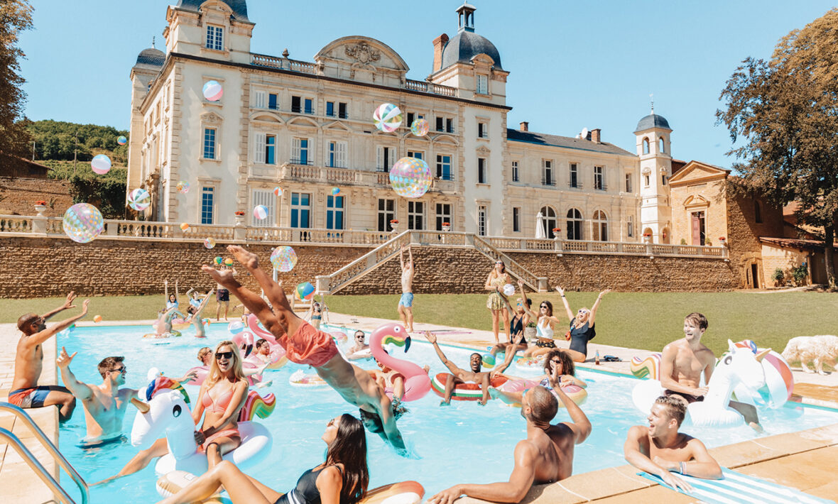 A group of people enjoying their gap year trips in a pool in front of a castle.