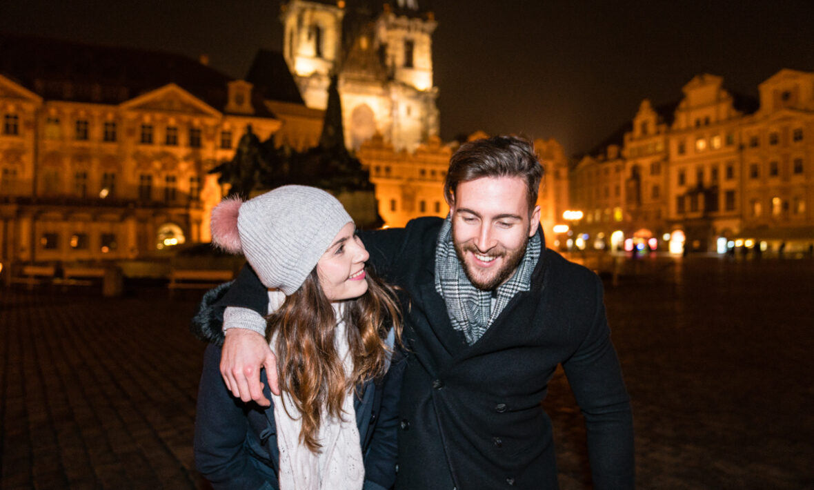 A couple standing in front of a church at night, embracing the moment.