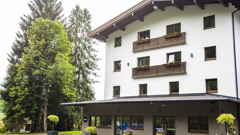 Gasthof Schoneck, a white building with balconies and trees in the background.