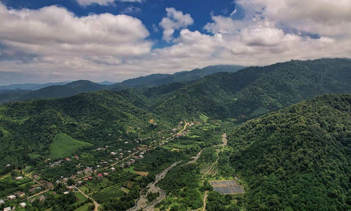 An aerial view of a green valley in Georgia with mountains.