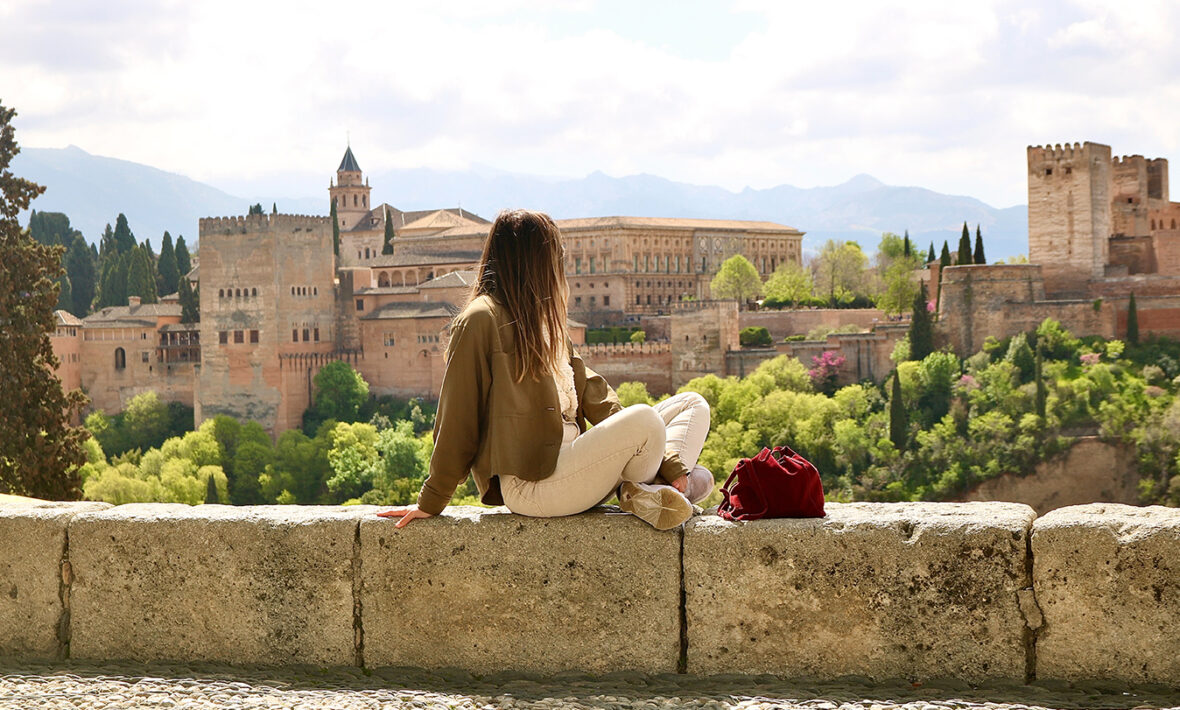 A woman is sitting on a wall in Granada.