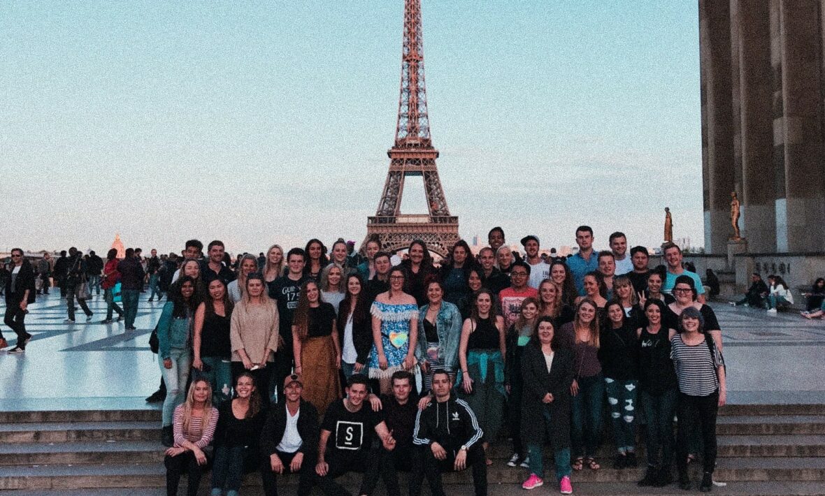 A group of people posing in front of the Eiffel Tower.