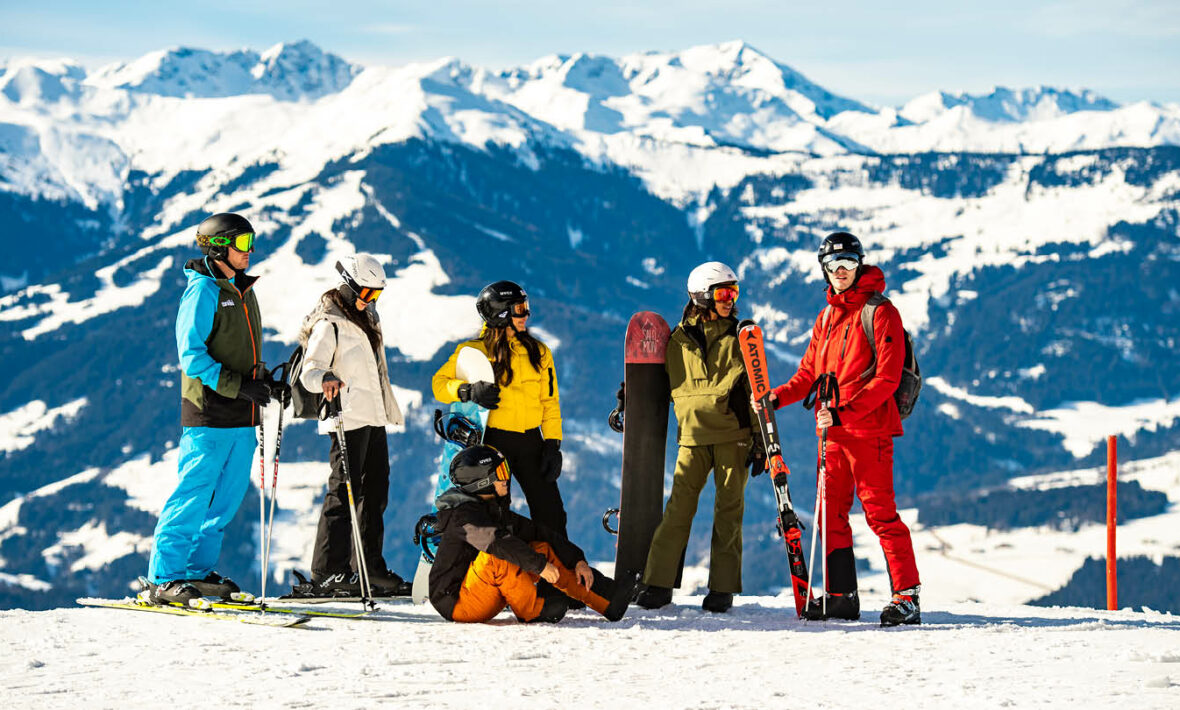 A group of people on a ski trip standing on top of a mountain.