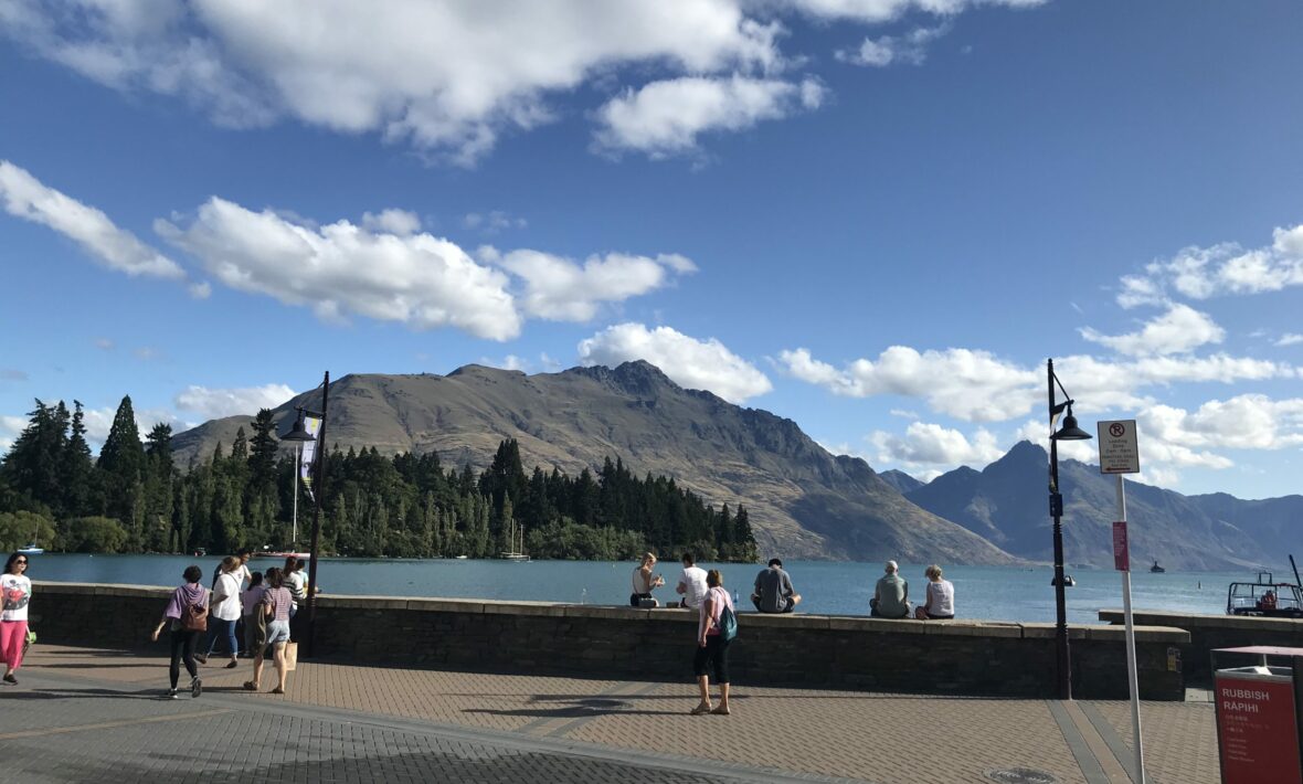 A group of people walking on a sidewalk near a lake.