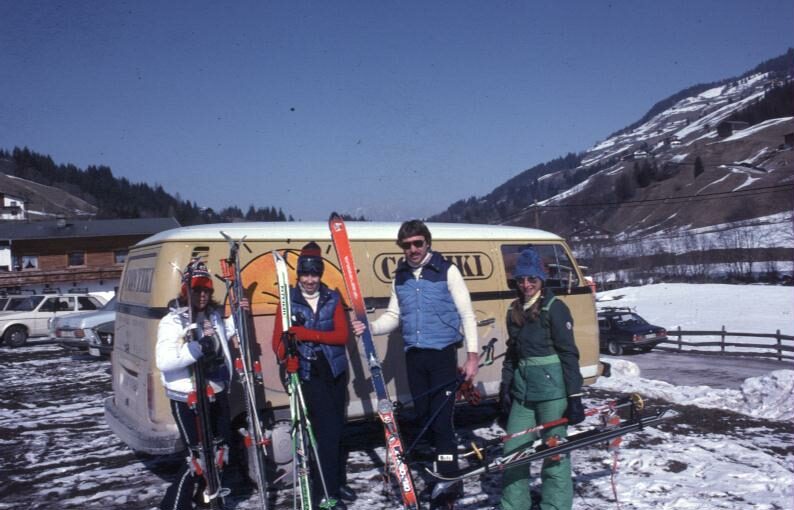 A group of people with skis and a van.