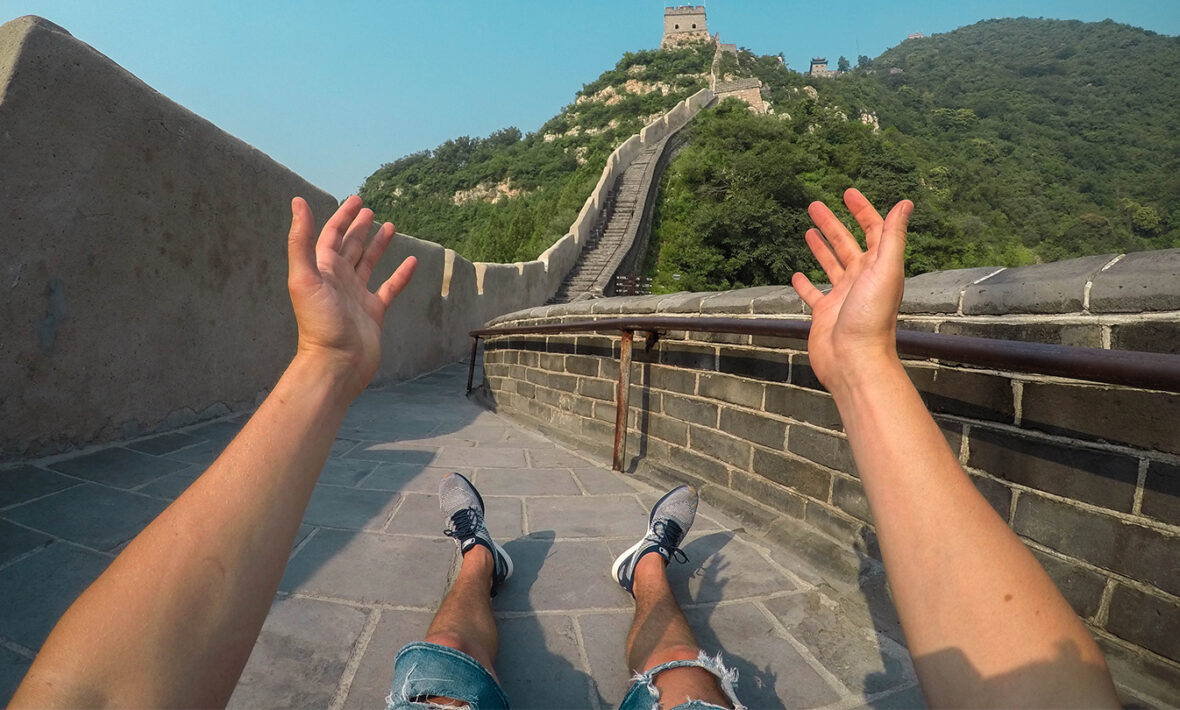 A person with their hands up on the great wall of china.