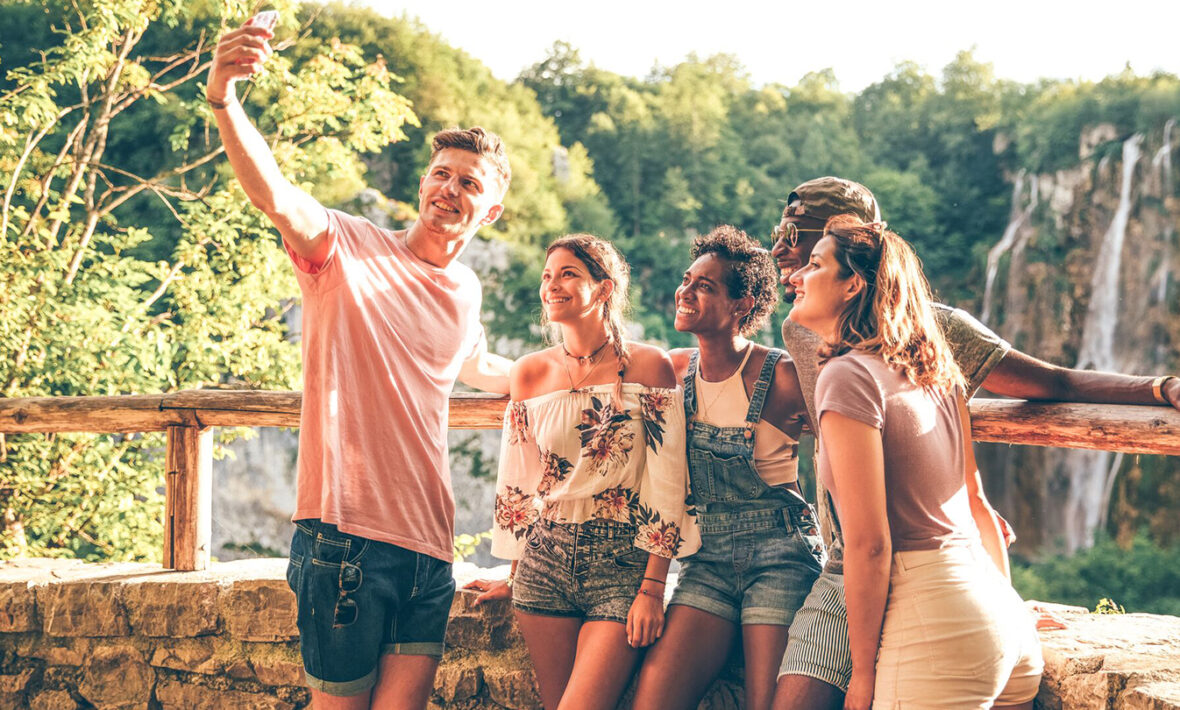 A group of friends taking a selfie in front of a waterfall.