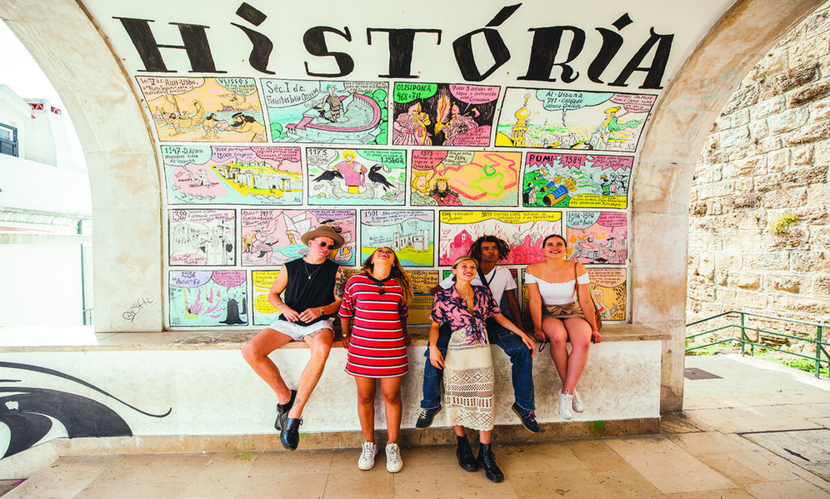 A group of people capturing local experiences in front of a mural.