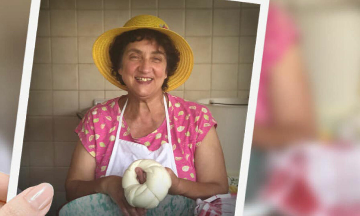 A woman in a hat holding a piece of bread on a farm.