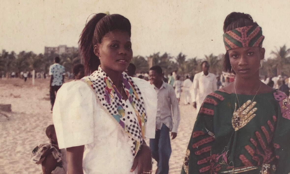 Two African women in traditional clothing standing on the beach.