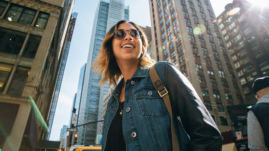 A woman in sunglasses and a denim jacket exploring NYC thrift shops.