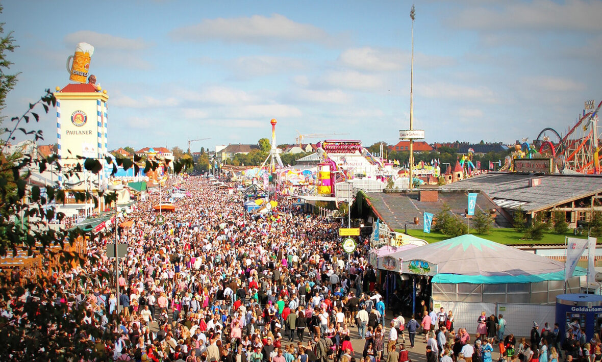 A crowd of people at an amusement park during Oktoberfest.