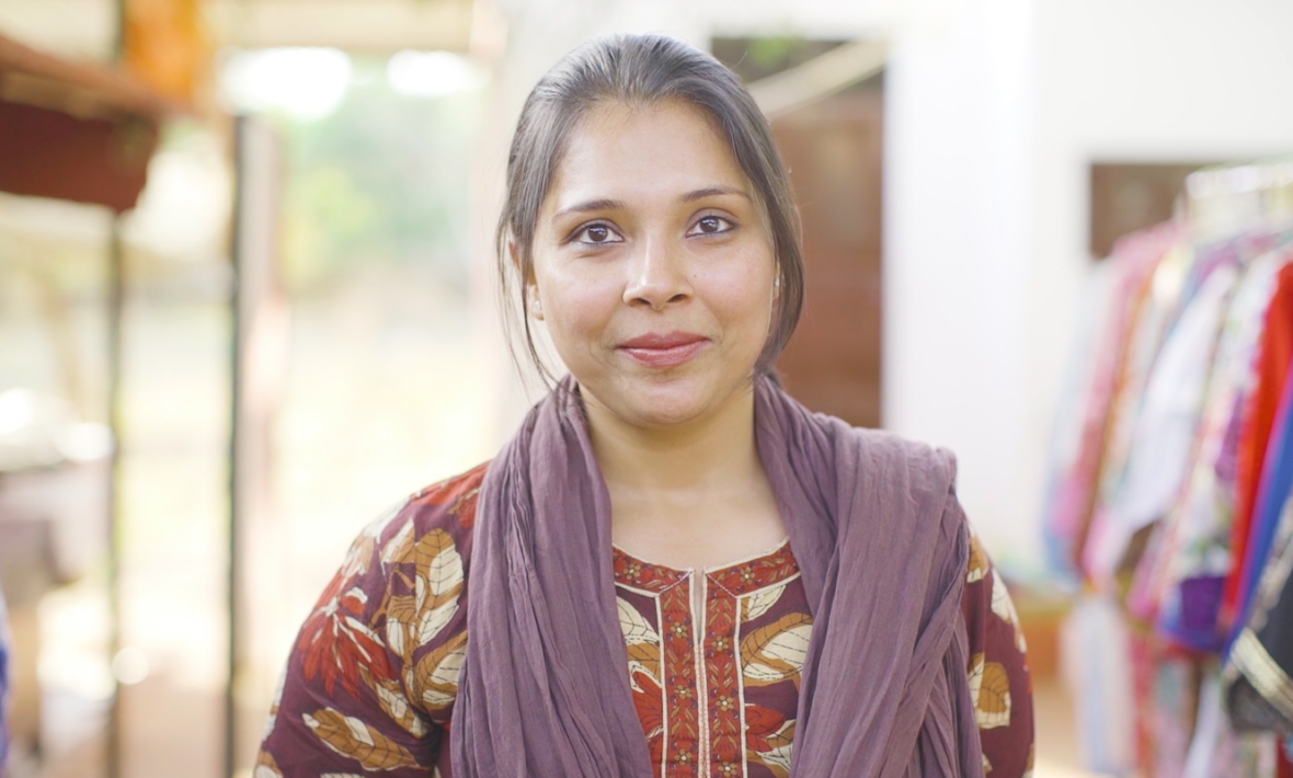 A woman standing in front of a rack of clothes at Dhonk crafts centre.