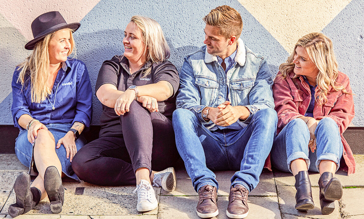 A group of contiki trip managers sitting in front of a wall.