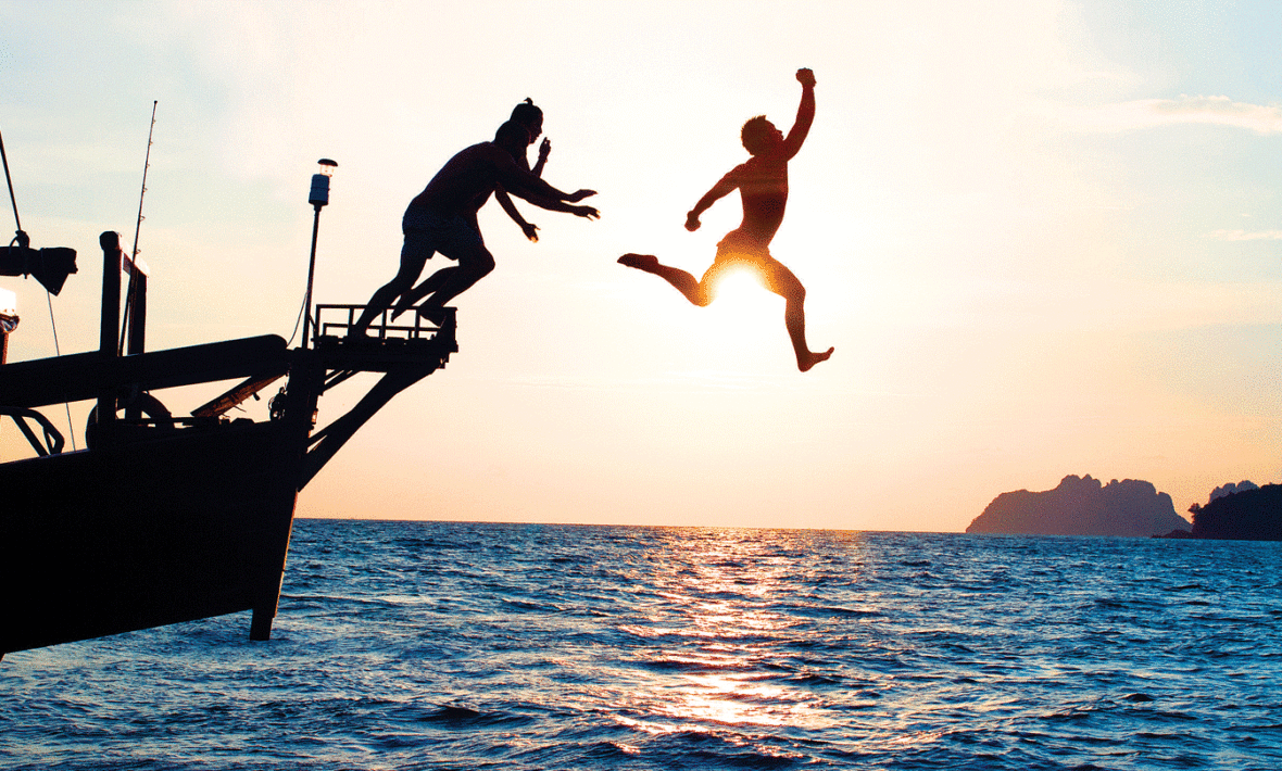 Two digital nomads jumping off a boat in Thailand.