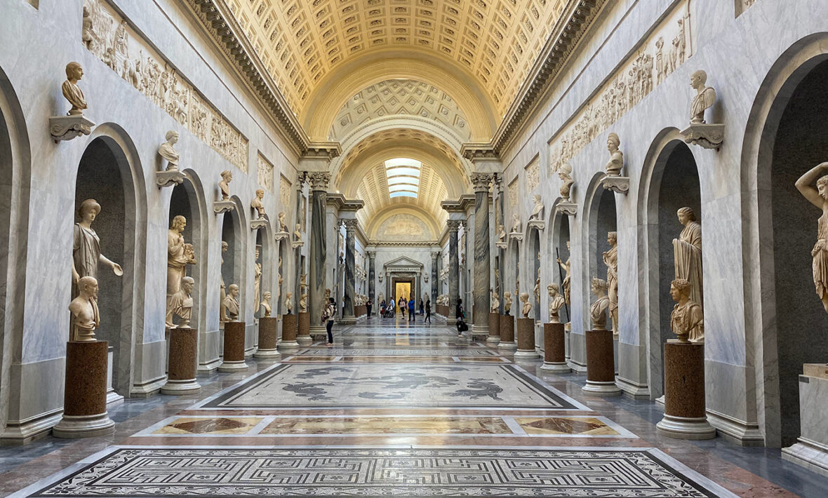 A hallway full of statues in a museum.