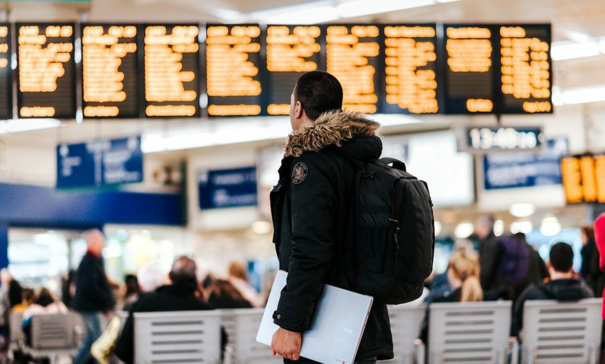 A man with a backpack carrying travel adapters in a train station.