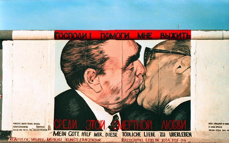 A captivating mural depicting two men kissing skillfully painted on a colorful Berlin wall.