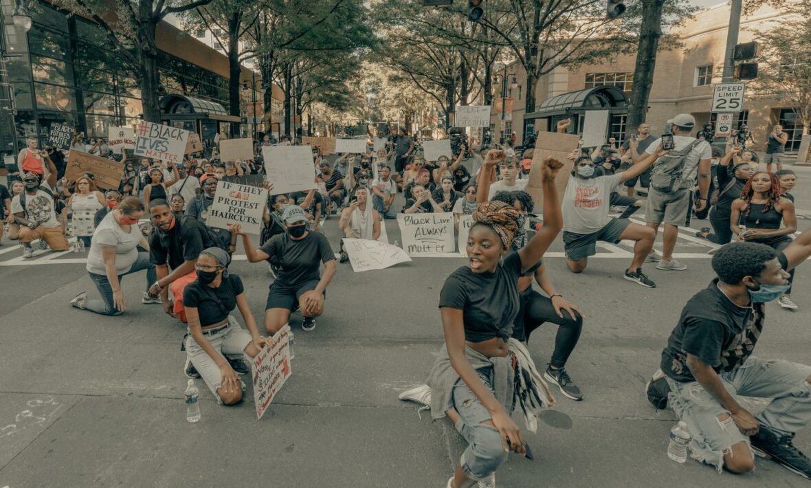 A group of people sitting on the street holding signs at Black Lives Matter marches.