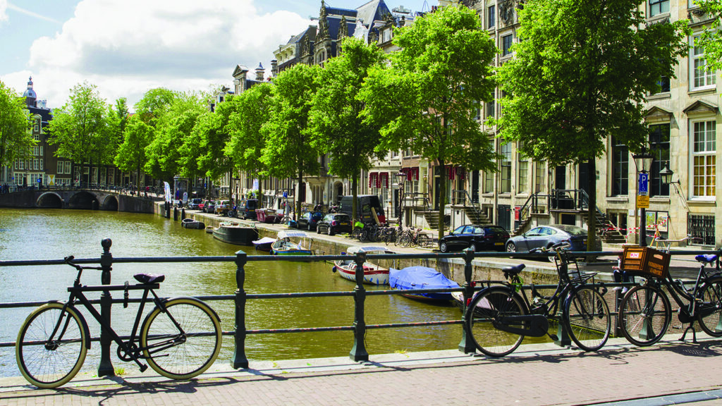 A bike parked on a railing next to a canal in Amsterdam.