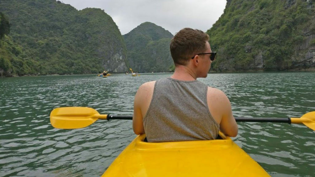 Dom Oliver is paddling a yellow kayak on a body of water.