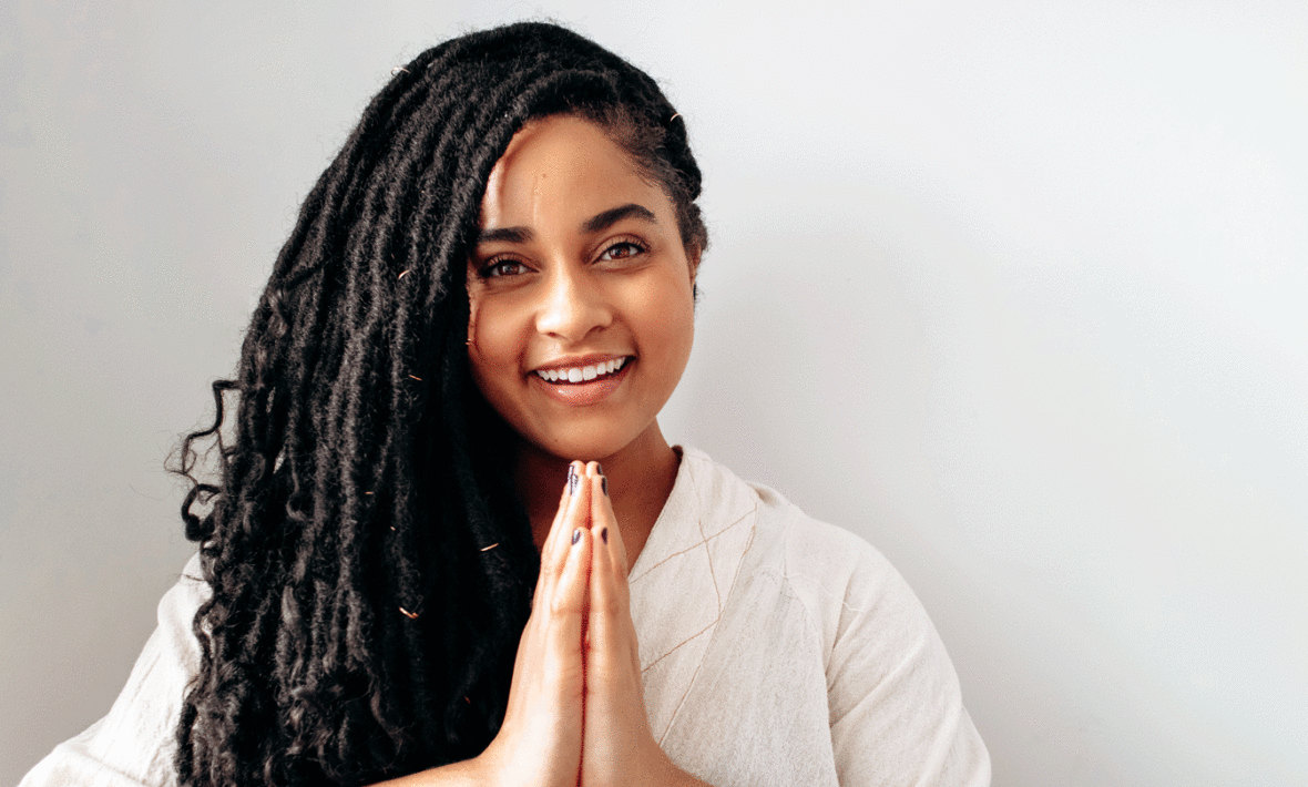 A young woman with dreadlocks positively smiling.