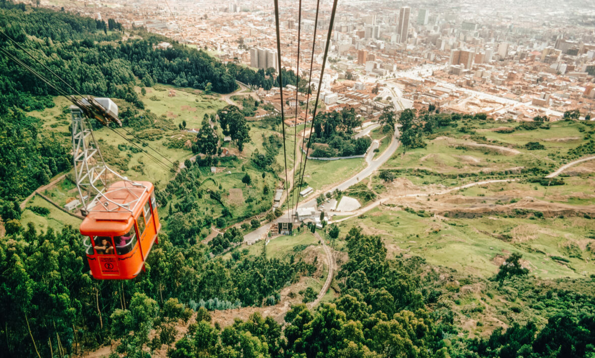 A cable car is flying over a city in colombia.