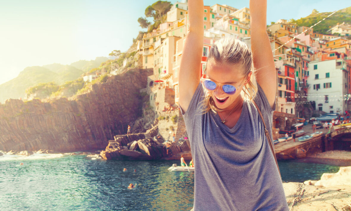 A woman with her arms up in the air, embracing self improvement in front of a city.