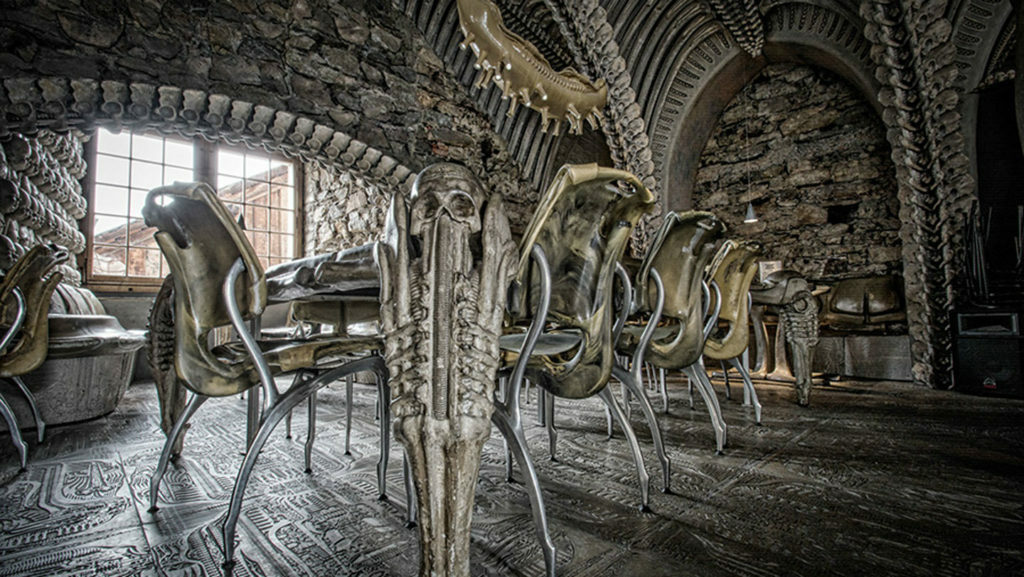 A spooky dining room in a stone building with metal chairs.