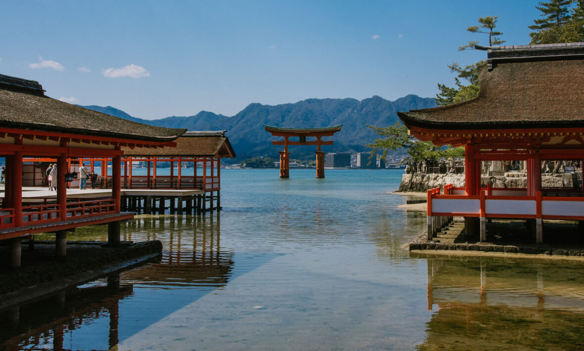 A red tori tori gate on the shore of a body of water in Japan.