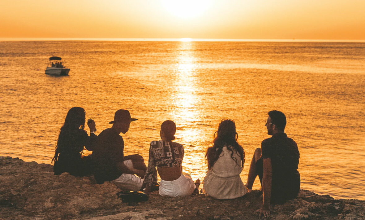 A group of people watching the sunset on a cliff, perfect for capturing the best travel movies.