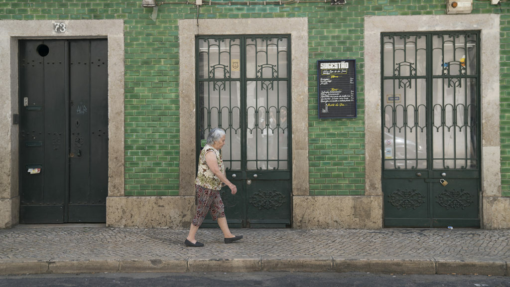 A woman travelling in front of a building.