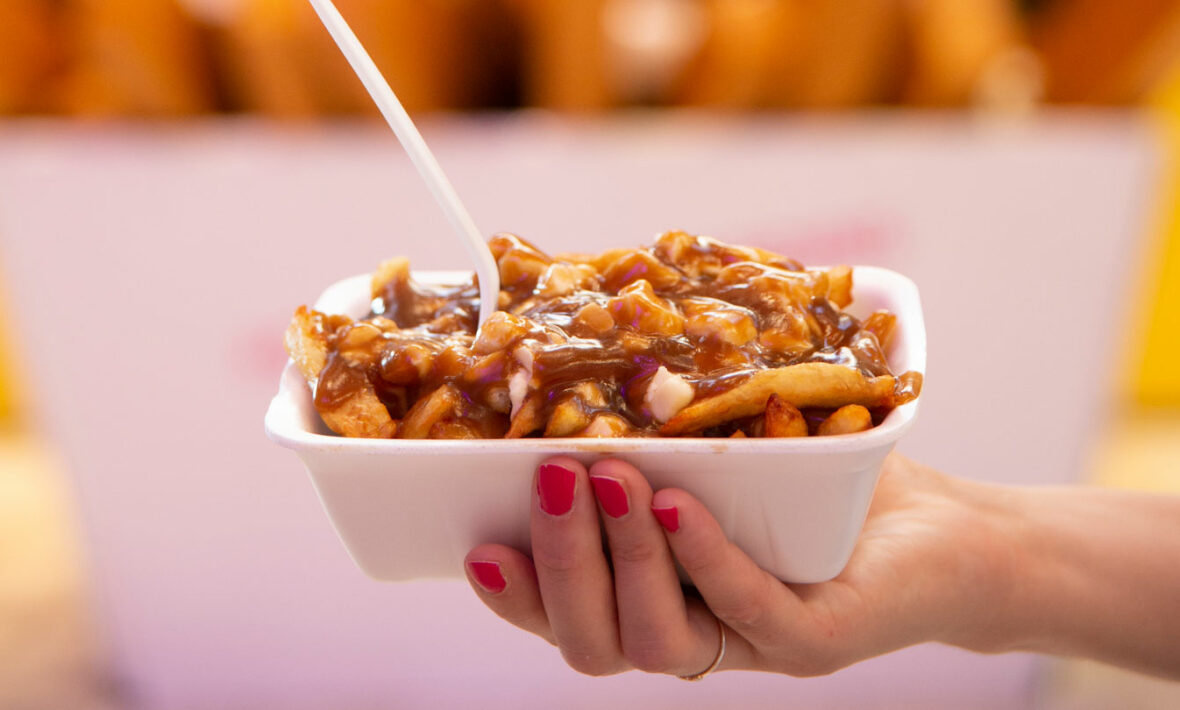 A person holding a bowl of fries and gravy, showcasing the best poutine in Montreal.